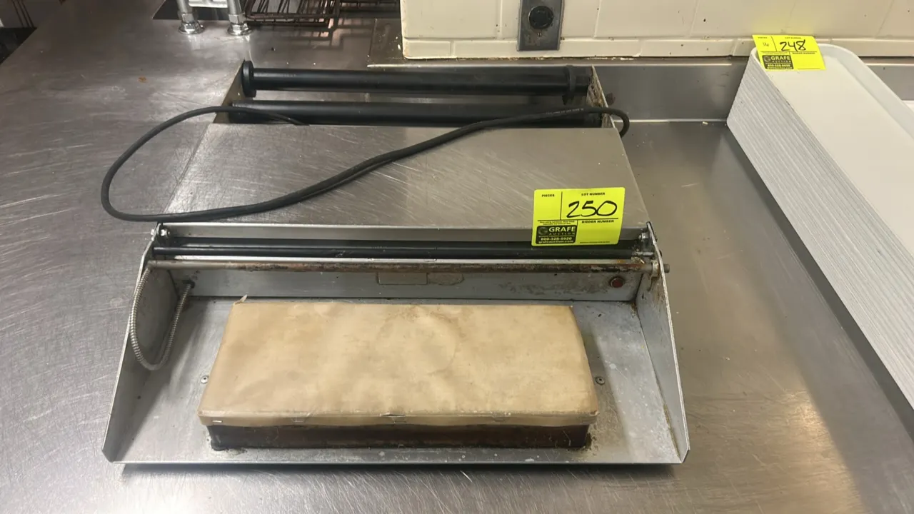 Heat Seal tabletop film wrapper. Features stainless steel construction, heated sealing hot plate, film cut-off rod, and film roll cradle rollers. Elec