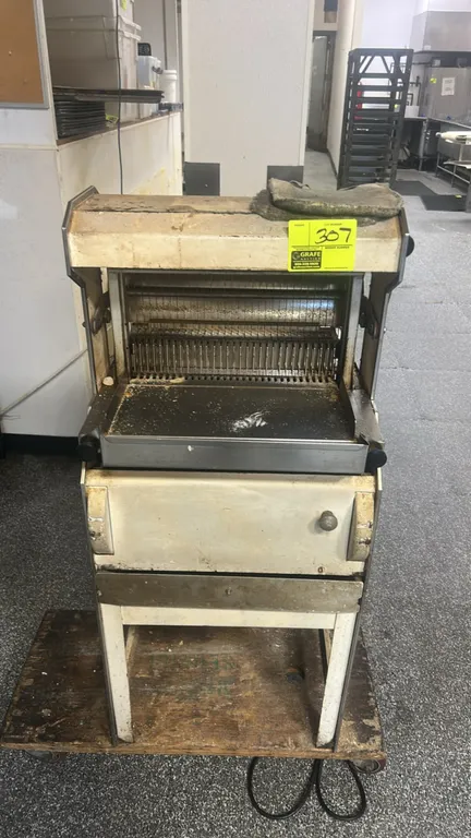 Oliver 777 gravity-feed bread slicer. Features stainless steel infeed and discharge trays and manual pusher lever. S/N: 101935. Electrical: 110V, 60 H