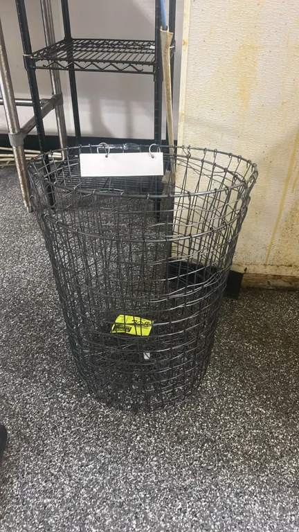 Metal wire basket. Features round tapered wire mesh construction and a hanging metal rim sign tag.
