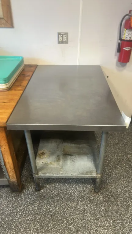 Stainless steel work table. Features a flat top and lower undershelf. 48" x 30". Mounted on tubular legs with adjustable feet.