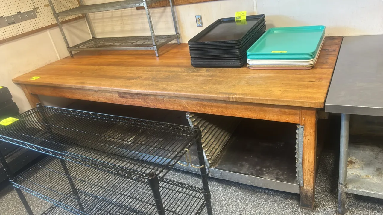 Wooden bakery table. Features a solid wood top, wood legs, stainless steel undershelf, and integrated sheet pan slides. Dimensions: 10' x 4'. Trays, c