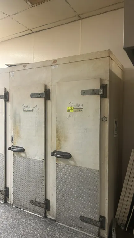 Hussmann foam panel walk-in cooler. Features (4) hinged doors with diamond plate kick plates, (2) Krack single-fan evaporator coils, and interior ligh