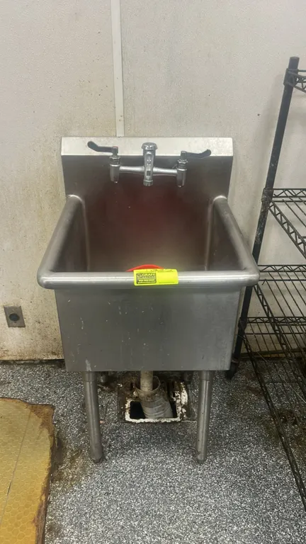 Stainless steel handwashing sink. Features single-basin compartment, integrated backsplash, splash-mount faucet with wrist-blade handles, and rolled e