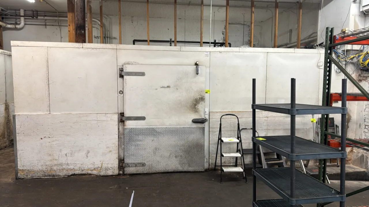 Hussmann foam panel walk-in cooler. Features pallet door with diamond plate kickplate, ceiling-mounted evaporator coils, and interior lighting. 22' x