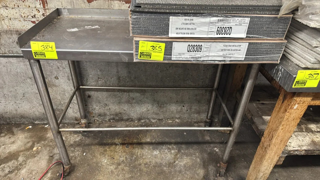 Stainless steel portable work table. Features a 3-sided backsplash and tubular cross-bracing. 44" x 20". Mounted on casters. Contents not included.