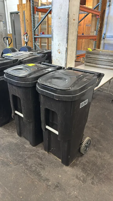 Rehrig Pacific HuskyLite ROC-35EG 35-gallon wheeled trash cans. Features black polyethylene construction, hinged flip lids, integrated handle, and fro
