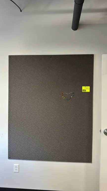 Fabric-covered cork bulletin board. Features charcoal textured woven fabric surface and matching fabric-covered fastener caps. Dimensions: 6' x 4'. Wa