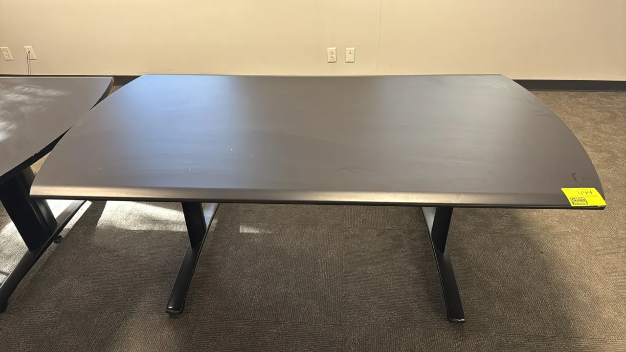 Laminated wood conference table. Features a dark laminate top with curved ends. Dimensions: 6' x 3'. Mounted on a black metal base.