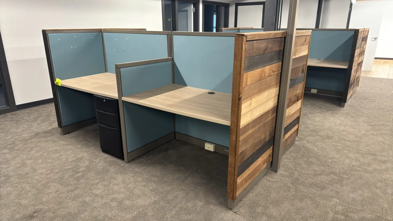 4-person cubicle workspace. Features blue fabric partition panels, rustic wood plank end panels, laminate desktops with cable grommets, and base racew