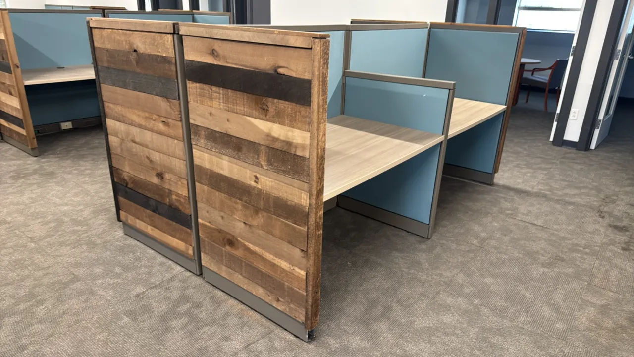 4-cubicle workspace. Features laminate work surfaces with cable pass-through grommets, blue fabric acoustic divider panels, rustic wood plank end pane