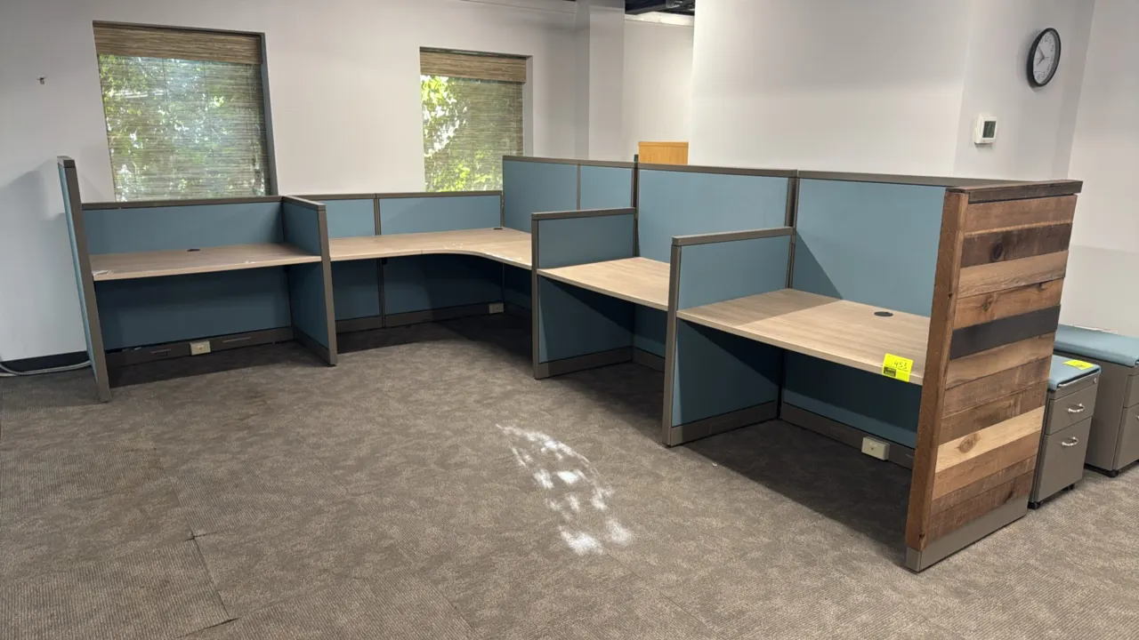 4-cubicle workspace system. Features blue fabric partition panels with metal frames, laminate desktops with wire pass-through grommets, and a rustic w