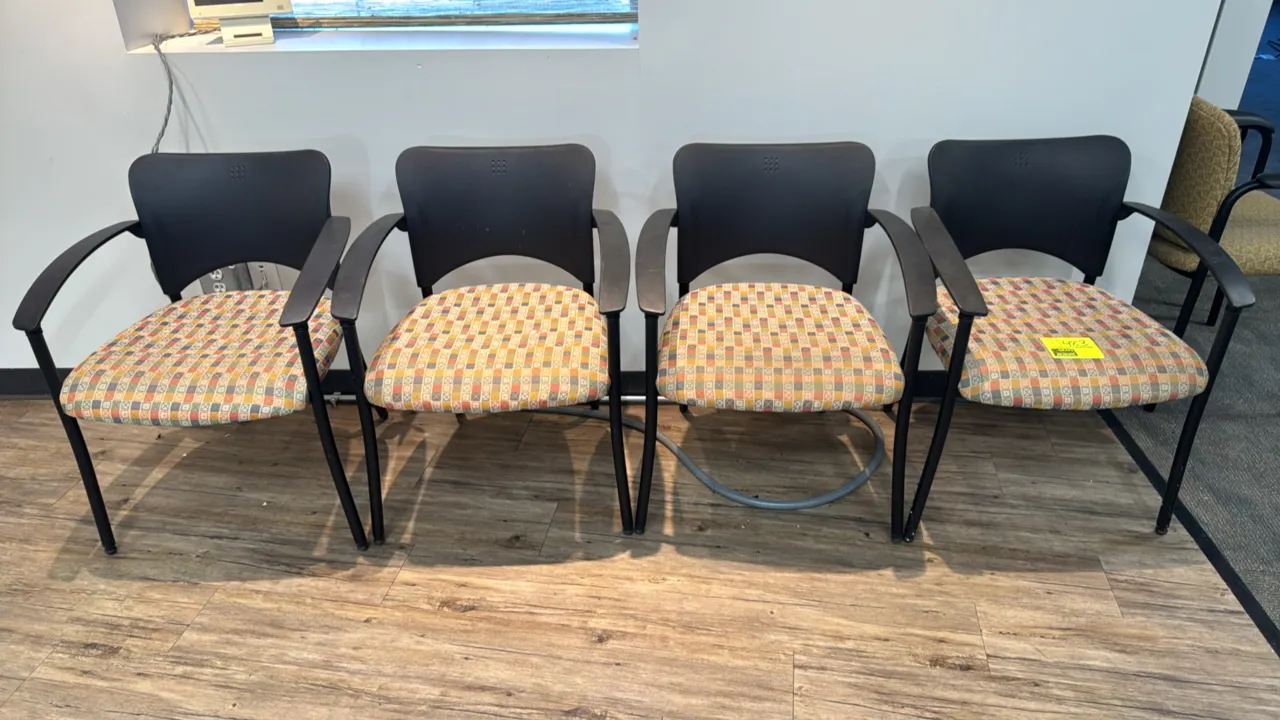 Teknion armchairs. Features multi-color patterned geometric upholstered padded seats, black contoured plastic backrests, and integrated armrests. Moun
