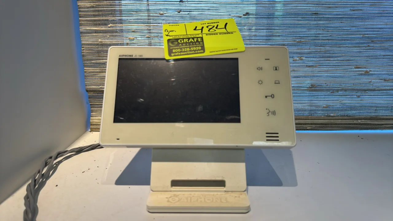 Aiphone JO-1MD video intercom master station. Features 7" color LCD screen, electrostatic touch controls, and hands-free communication. Mounted on an
