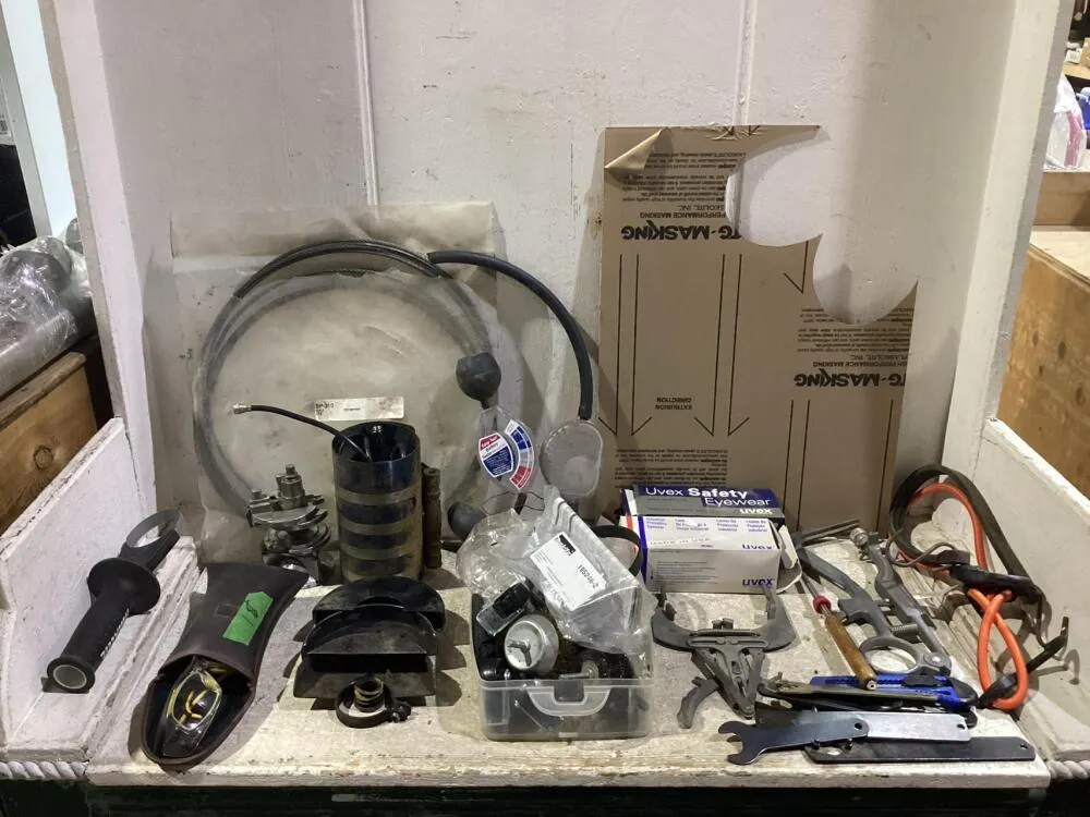 SHOP BOX OF MISCELLANECOUS W/ SAFETY GLASSES, BATTERY TESTER, OIL WRENCH, ANGLE GRINDER GUARDS & METAL WIRE