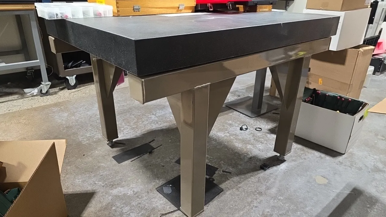 Precision granite surface plate. Dimensions: 36" x 47.5" x 4" (granite slab). Mounted on an industrial steel leveling stand with adjustable feet. Cont