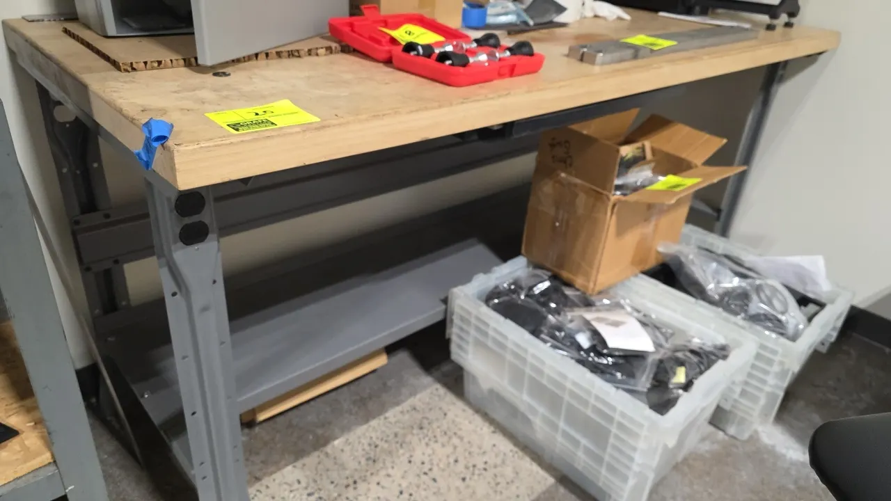 Wood top workbench. Features a wood work surface, gray metal frame, and lower metal undershelf. 72" x 30". Contents not included.