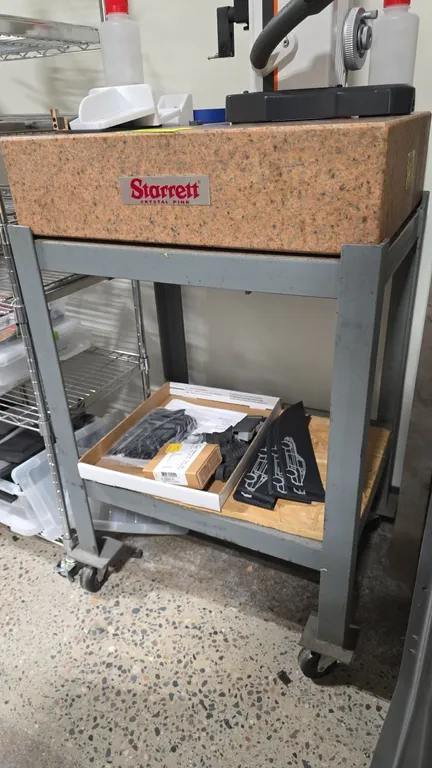 Starrett Crystal Pink granite surface plate. Grade A Inspection. S/N: 993683. Dimensions: 24" x 18" x 6". Mounted on a rolling metal cart with casters
