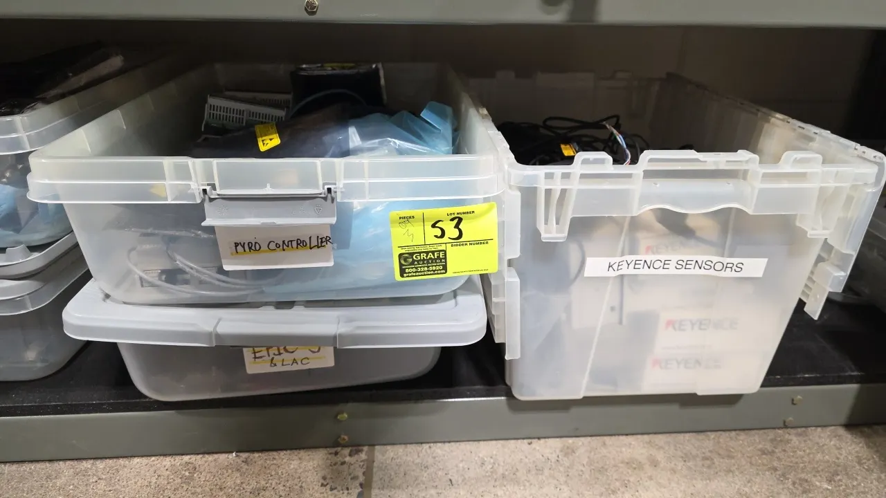 Plastic storage totes with assorted industrial sensors, controllers, and wiring components. Includes Keyence sensors and accessories (including model