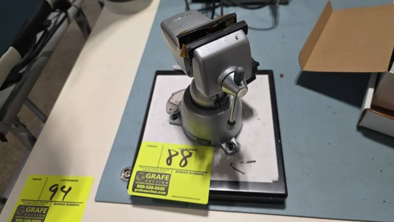 PanaVise bench vise. Features 2-1/2" jaws, adjustable swivel ball mount with locking knob, and protective jaw pads. Mounted to an 8" x 8-1/2" base pla