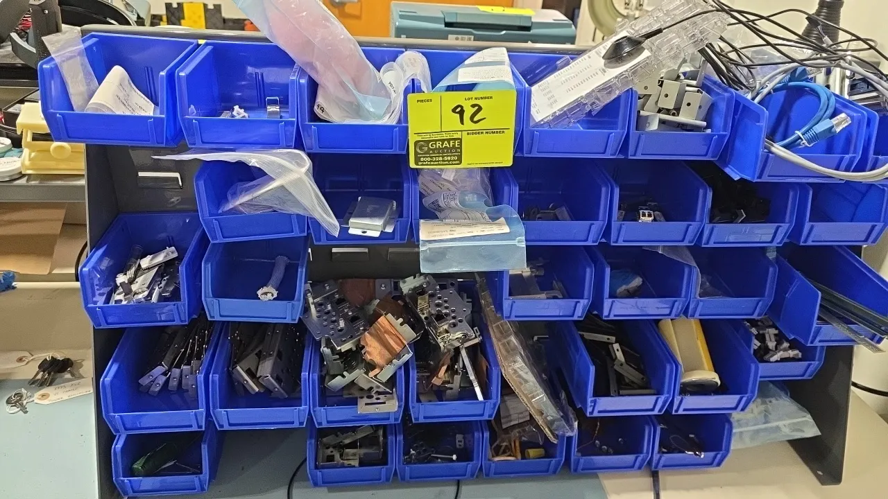 Metal countertop parts organizer stand. Features multi-tier louvered rack construction. Includes blue plastic hanging bins and assorted parts and hard