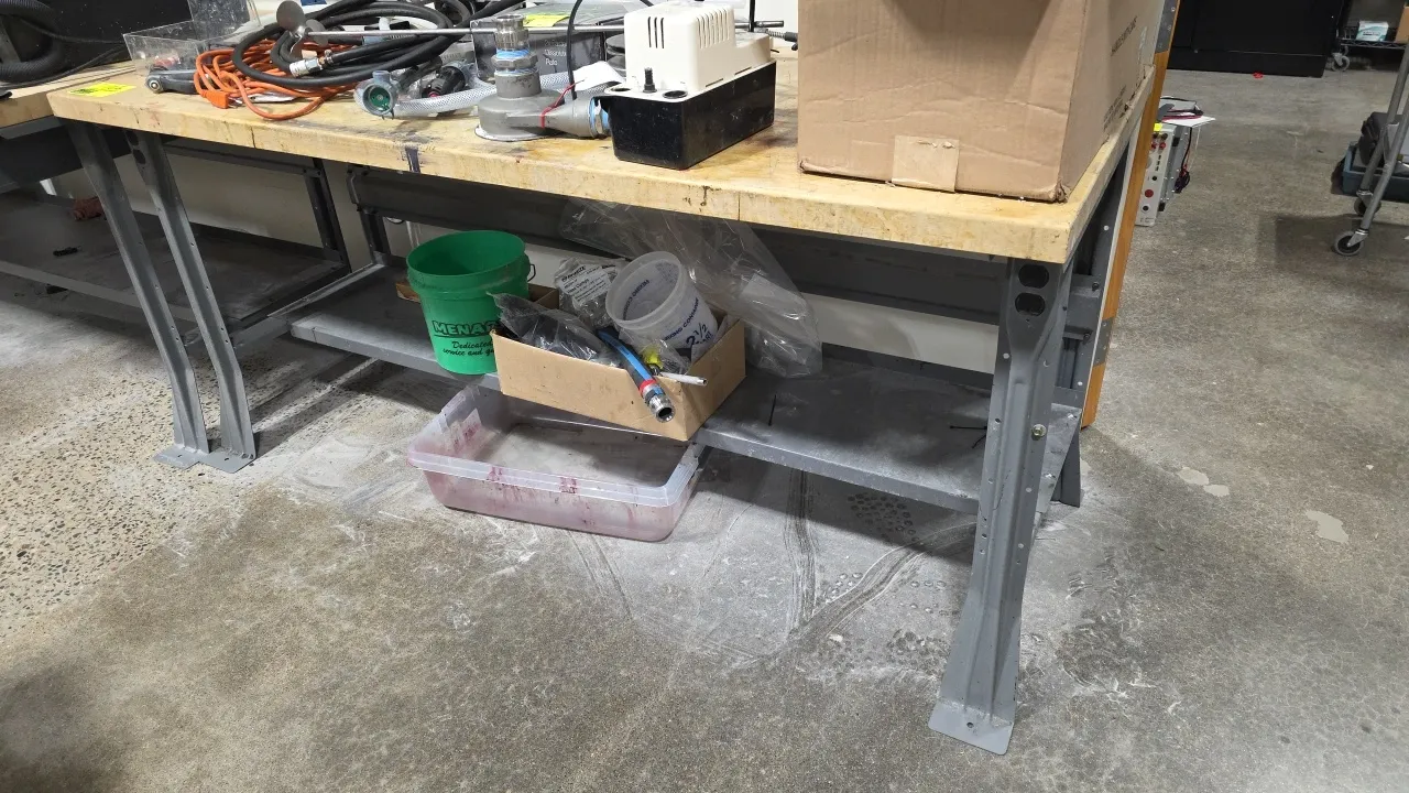 Industrial workbench with lower storage shelf. Features a thick wood work surface and painted steel frame and legs. 72" x 30". Contents not included.