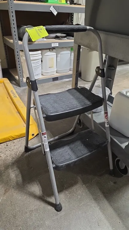 Werner StepRight 2-step folding step stool. Features a tubular metal frame, dual textured slip-resistant plastic steps, padded hand grip, and non-marr