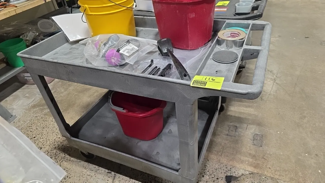 Poly 2-tier utility cart. Features molded push handle with integrated tool and accessory compartments and two deep-lipped shelves. Mounted on casters.