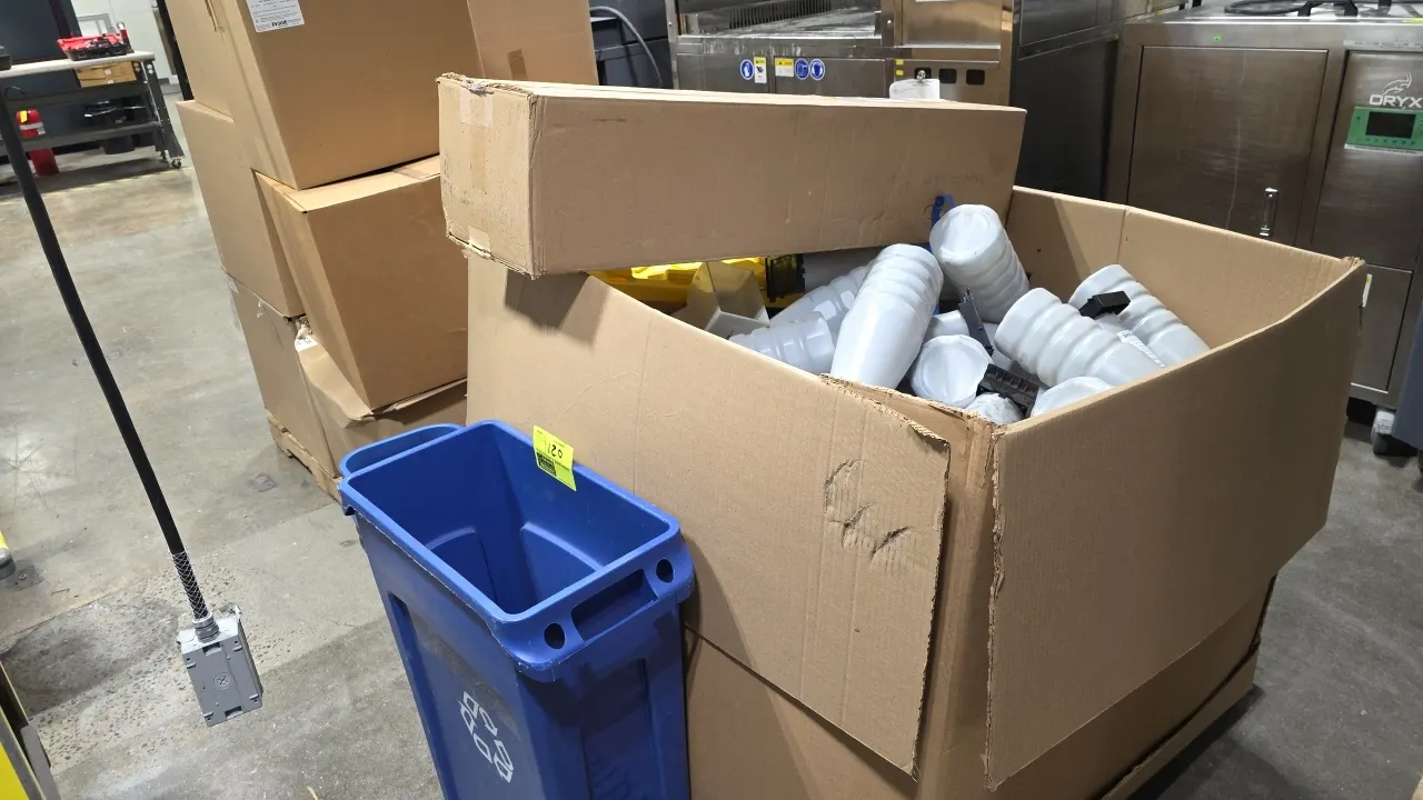 Waste receptacle and toner cartridge package lot. Includes blue Rubbermaid Slim Jim 3540-60 recycling receptacle, stacked plastic wastebaskets, and bu