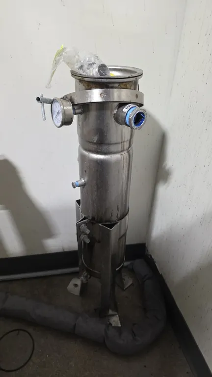 Stainless steel liquid bag filter housing. Features top clamp-ring closure lid, 0-30 PSI pressure gauge, threaded inlet and outlet ports, and bottom d