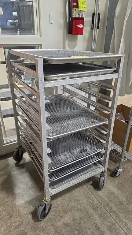 Aluminum sheet pan rack cart. Includes (2) full-size sheet pans, (7) half-size sheet pans, and wire cooling racks. Features angle runner slides and to