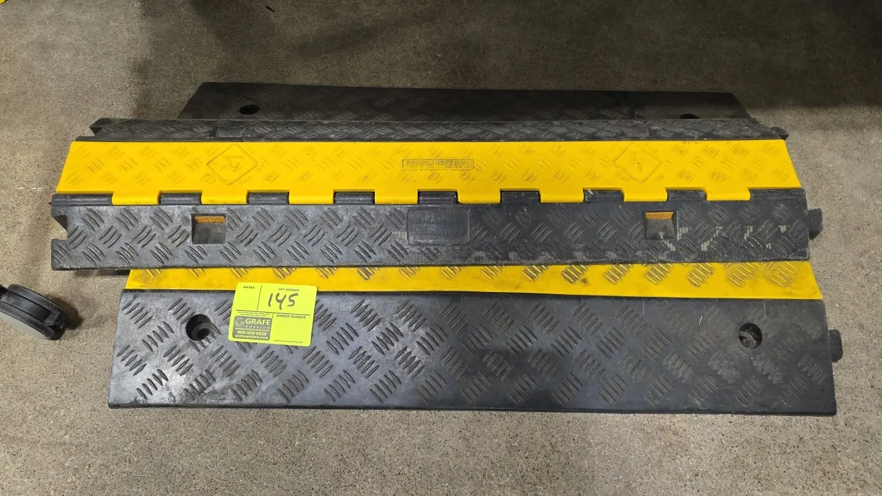 Rubber cable and hose protectors. Features heavy-duty black rubber bases with textured traction surfaces, yellow flip-top hinged lids, and interlockin