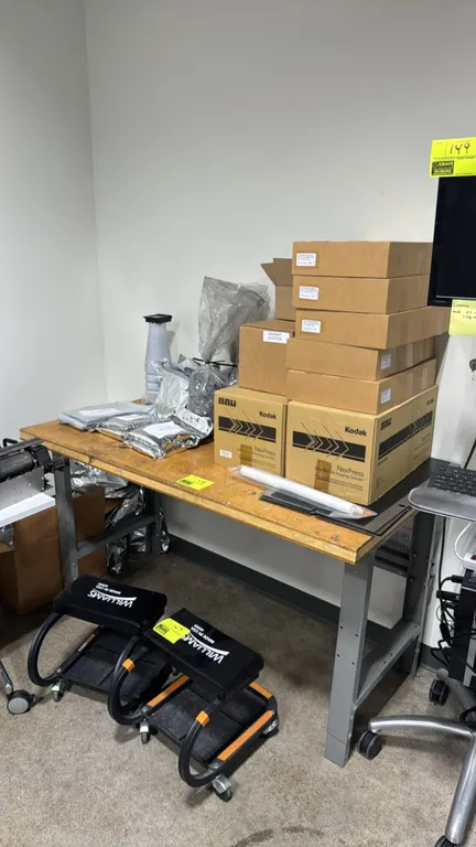 Metal workbench with wood top and assorted printing consumables. Includes Kodak NexPress extended life imaging cylinders, toner, developer powder, and