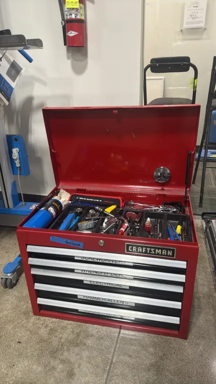 Craftsman 5-drawer metal tool chest. Features a top storage compartment with gas strut lid support and key lock. Includes assorted hand tool contents