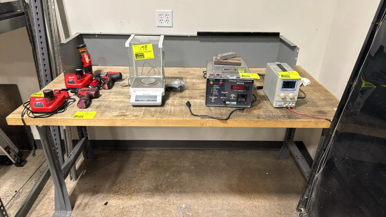 Industrial workbench. Features a butcher block wood top, painted steel frame with lower cross brace, and metal back and end stop riser. 6' x 3'. Conte