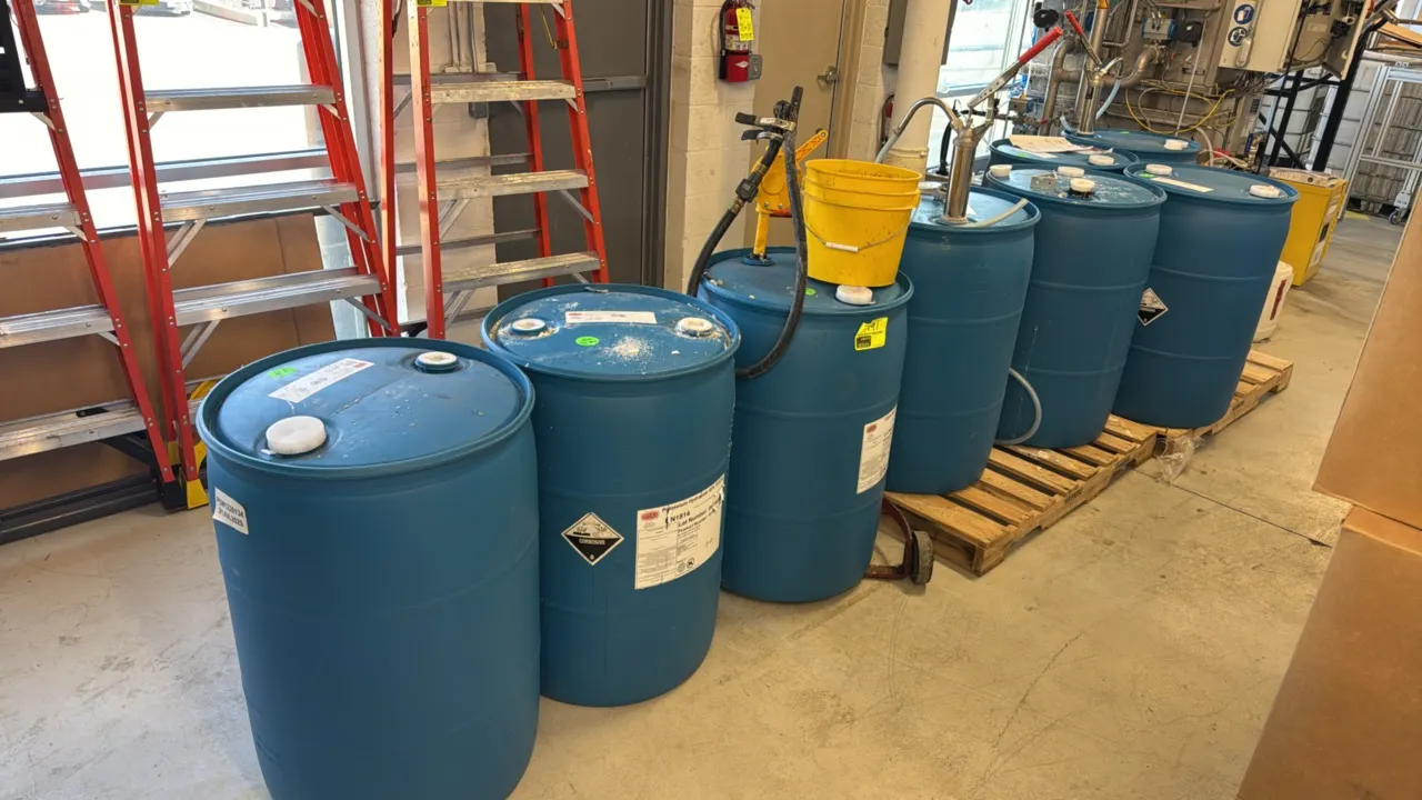 Chemical handling package lot. Includes (8) poly chemical drums, manual pumps, and a drum dolly. Features blue poly drums with Hawkins chemicals inclu