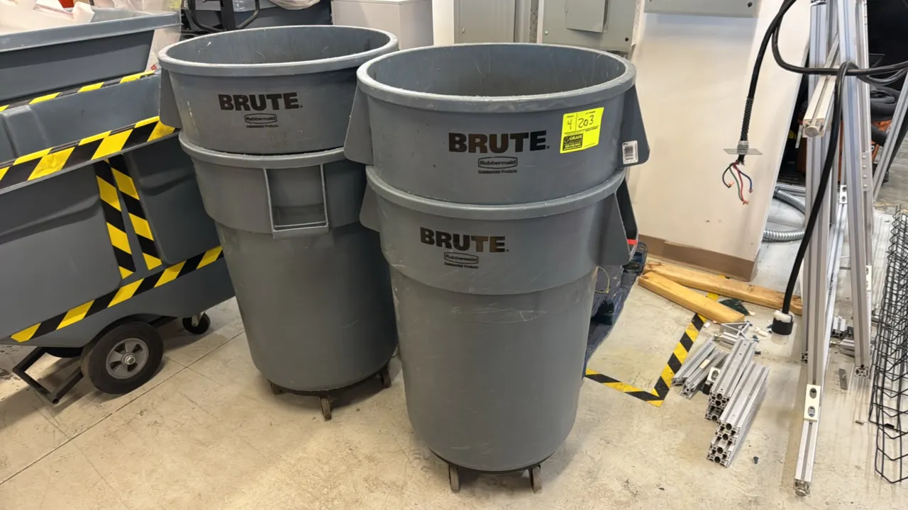 Rubbermaid Brute polyethylene trash cans. Features gray molded plastic construction with integrated side handles. Includes (4) cans, with (2) mounted