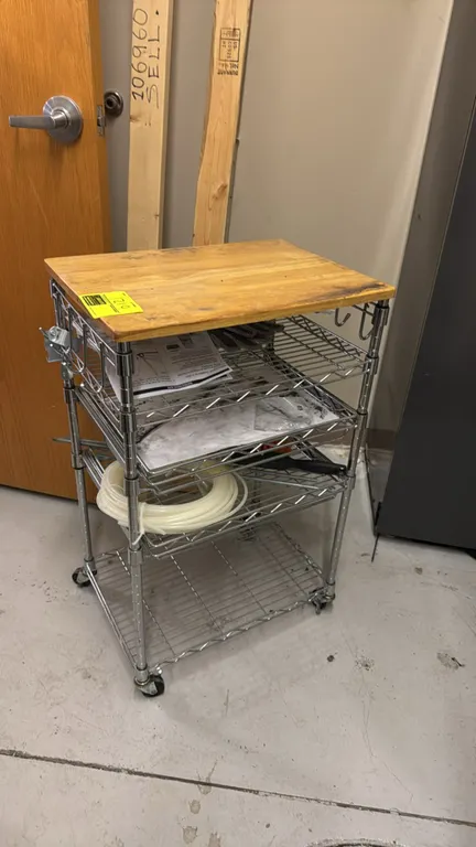 Chrome multi-tier portable wire rack with wood top. Features wire shelving and side hanging hooks. 21" x 15" x 34". Mounted on casters. Contents not i