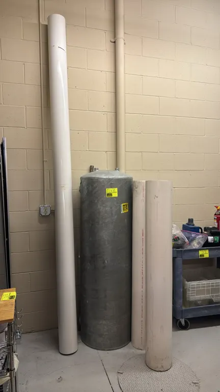 Galvanized metal 75 PSI tank with assorted 6" and 8" PVC pipes. Tank features threaded connection ports and a maximum working pressure rating of 75 PS