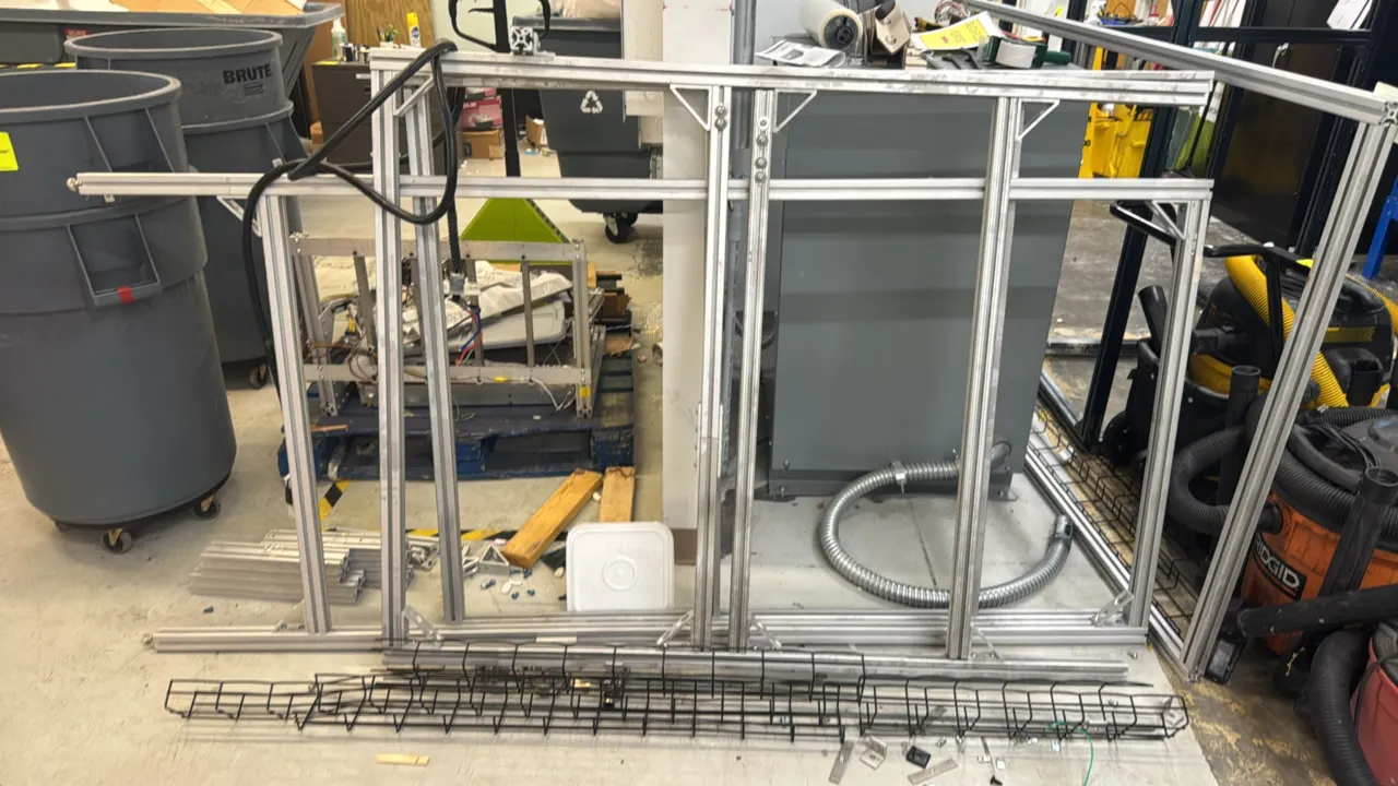Assorted T-slot extruded aluminum frames and components. Includes assembled frame sections, loose extrusion pieces, corner brackets, wire mesh cable m