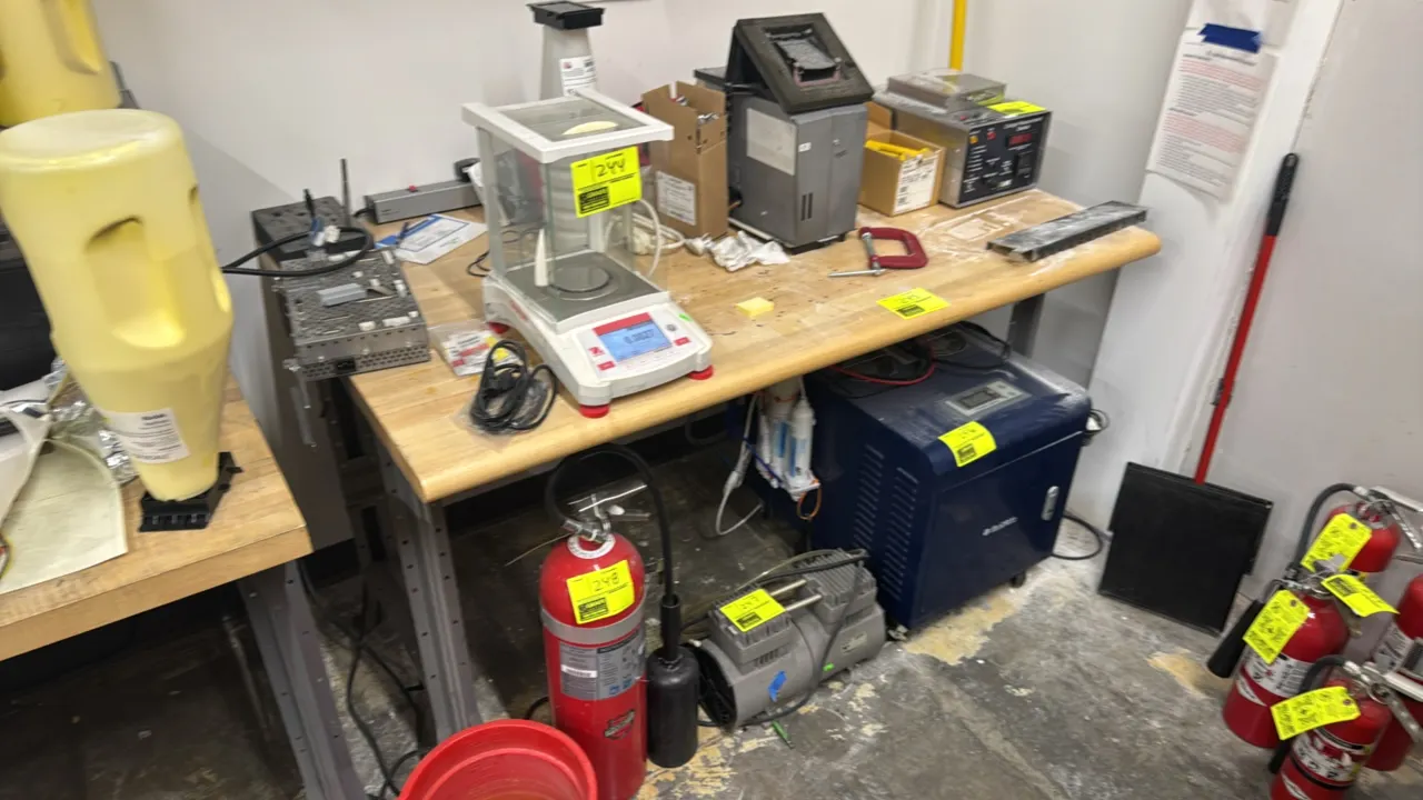 Workbench with wood top. Features a laminated wood top with a bullnose front edge and a gray metal frame. 5' x 3'. Contents not included.