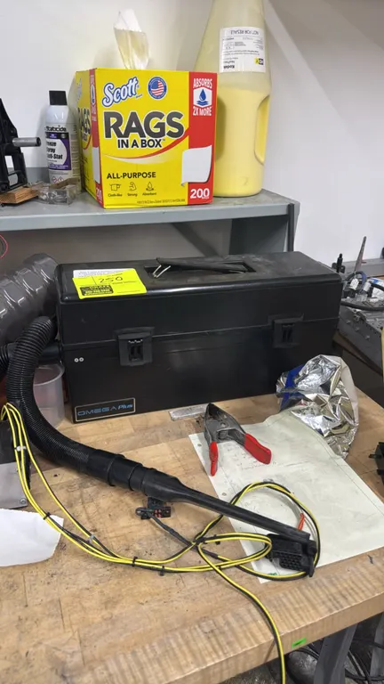 Atrix Omega Plus portable electronic service vacuum. Features tool box style enclosure with top carry handle, dual latches, flexible hose, and nozzle