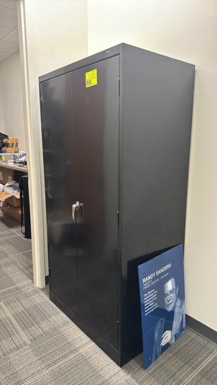 Tennsco metal 2-door storage cabinet. Features dual hinged doors with a locking handle and adjustable interior shelves. Finished in black. Dimensions: