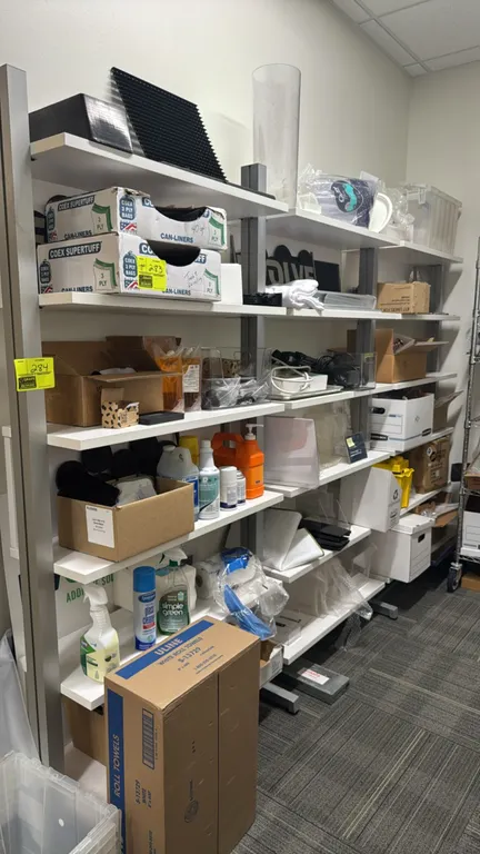 Metal and laminate 6-tier shelving rack. Features gray metal uprights and white laminate shelves across three bays. Dimensions: 116" x 18" x 81". Cont