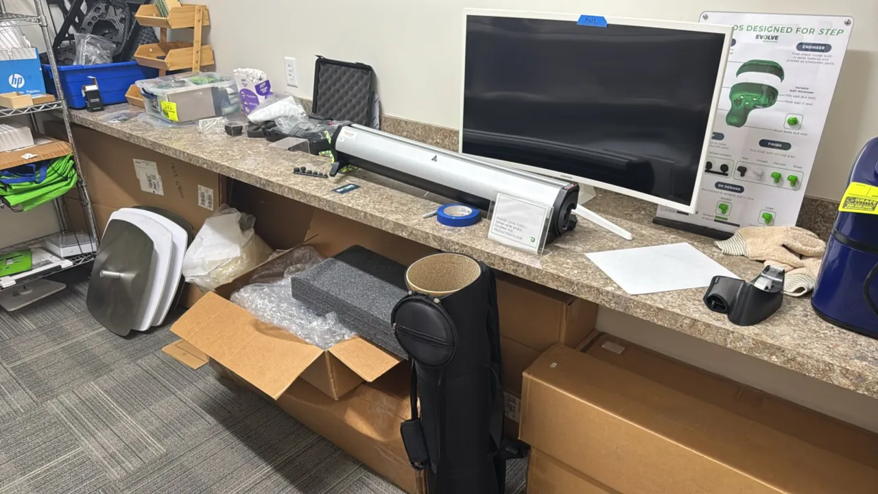 Package lot of assorted office and display items located on and under counter. Includes a Samsung curved monitor, TigerLink retractable banner stand c