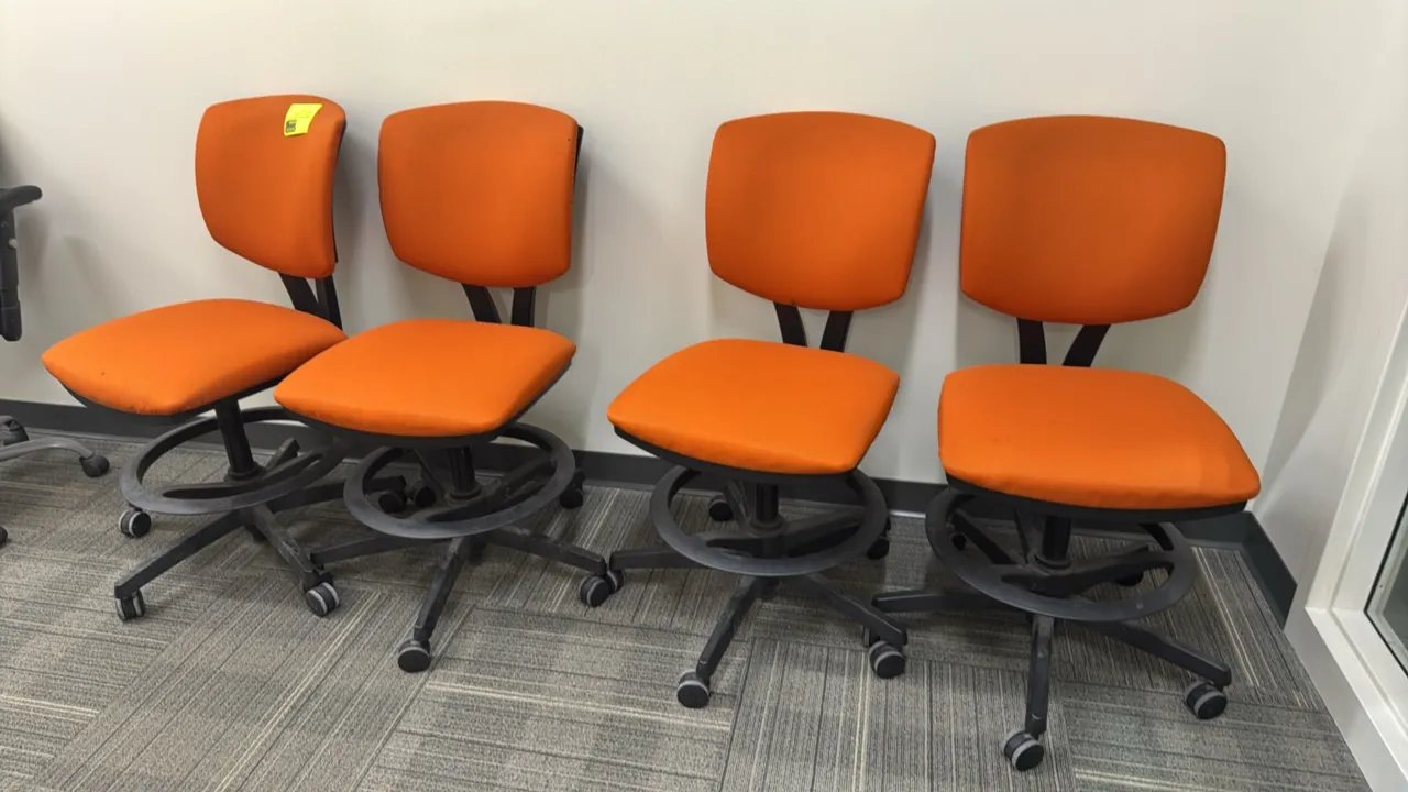 HON upholstered counter-height chairs. Features orange padded fabric seat and back, armless design, integrated foot ring, and black 5-star base with c