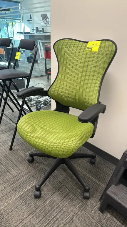 Mesh-back office chair. Features a lime green patterned mesh back, matching upholstered seat cushion, and black flip-up armrests. Mounted on a 5-star