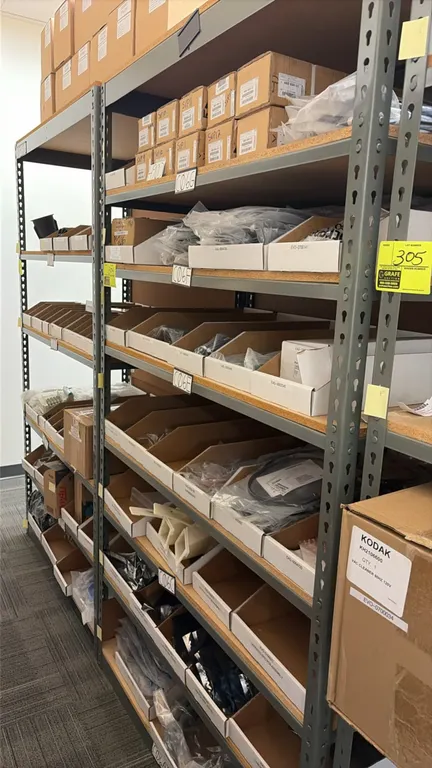 Light-duty metal shelving unit. Features particle board decking. 48" x 24" x 84". Includes assorted industrial parts, wiring harnesses, PCB assemblies