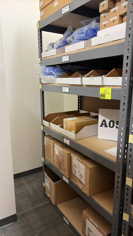 Light-duty steel shelving unit with contents. Features particle board shelf decking. Includes assorted inventory: plastic tubing, pneumatic components