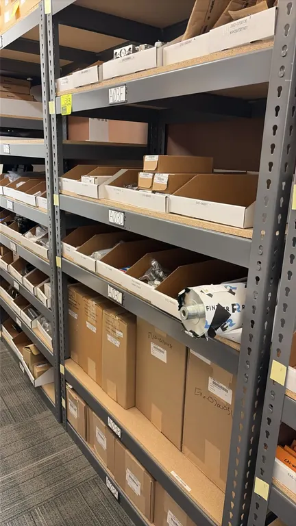 Light-duty racking with contents. 48" x 24" x 84". Includes wire harnesses, small motors, roller, pneumatic cylinders, and assorted replacement parts.
