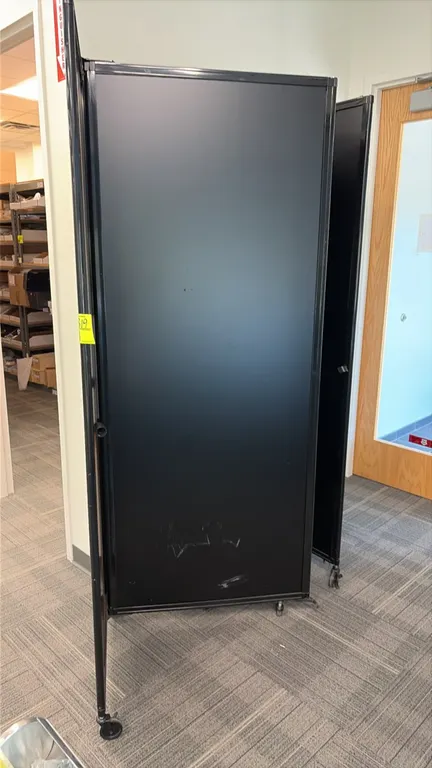 Portable 5-panel folding room divider. Features black panels and hinged metal frame. Mounted on casters.